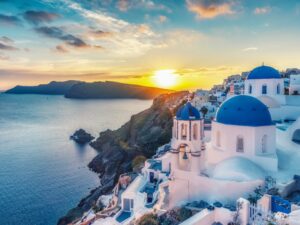 Beautiful view of Churches in Oia village, Santorini island in Greece at sunset, with dramatic sky.