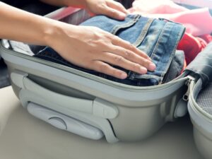 Close up of businesswoman packing clothes into travel bag - Luggage and people concept