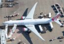 Virgin Australia Boeing 777-300ER parked at an airport gate with services