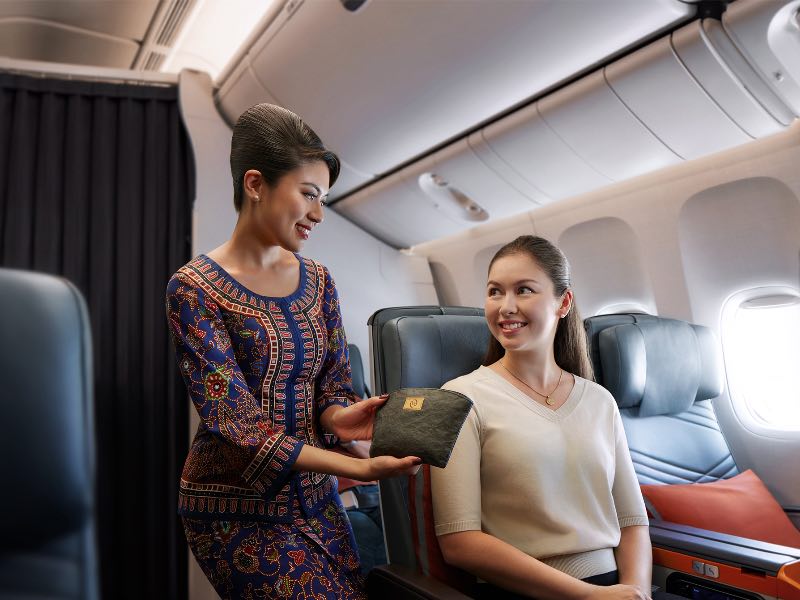 Singapore Airlines flight attendant giving an amenity kit in premium economy