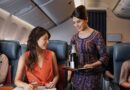 Singapore Airlines flight attendant offers champagne to premium economy passenger