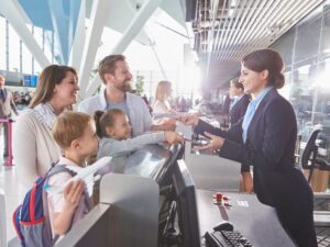 Family checking in at airport with boarding passes being handed over