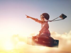 Dreams of travel! Child flying on a suitcase against the backdrop of a sunset.