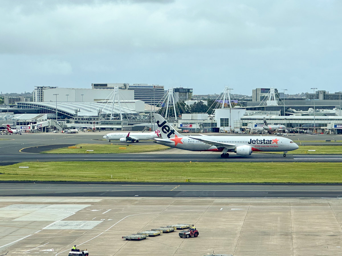 Jetstar Boeing 787-8 lands at Sydney Airport, with Virgin Australia plane in the background