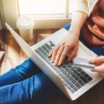 Woman is holding credit card and using laptop computer. Online shopping concept.