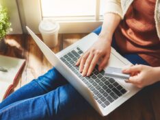 Woman is holding credit card and using laptop computer. Online shopping concept.