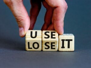 You use or lose it symbol. Concept word Use It or lose it on wooden cubes. Beautiful grey table grey background. Businessman hand. Business and you use or lose it concept
