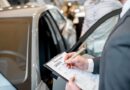 Manager filling car rental documents standing in the showroom with car on the background