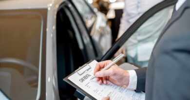 Manager filling car rental documents standing in the showroom with car on the background