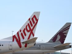 Qatar Airways Boeing 777 behind a Virgin Australia 737 tail at Brisbane Airport