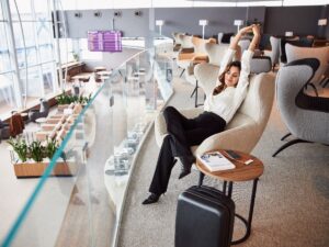 Lady sitting in chair and stretching while waiting for flight in departure airport lounge