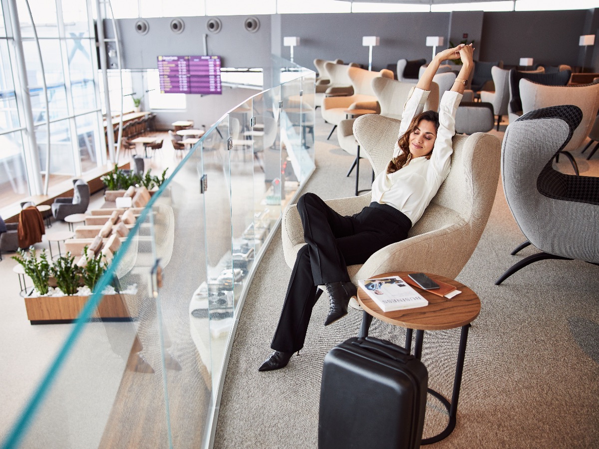 Lady sitting in chair and stretching while waiting for flight in departure airport lounge