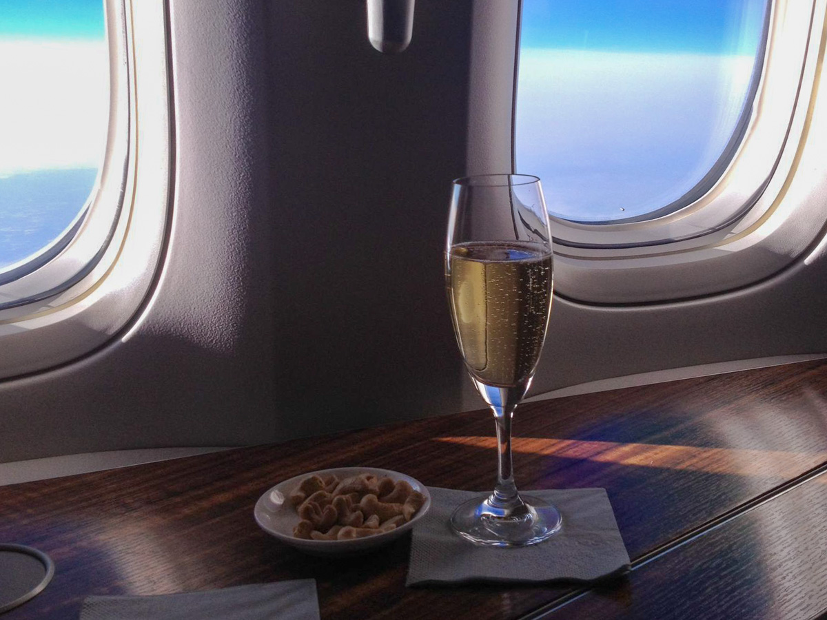 A glass of champagne in Cathay First class and blue sky outside the windows