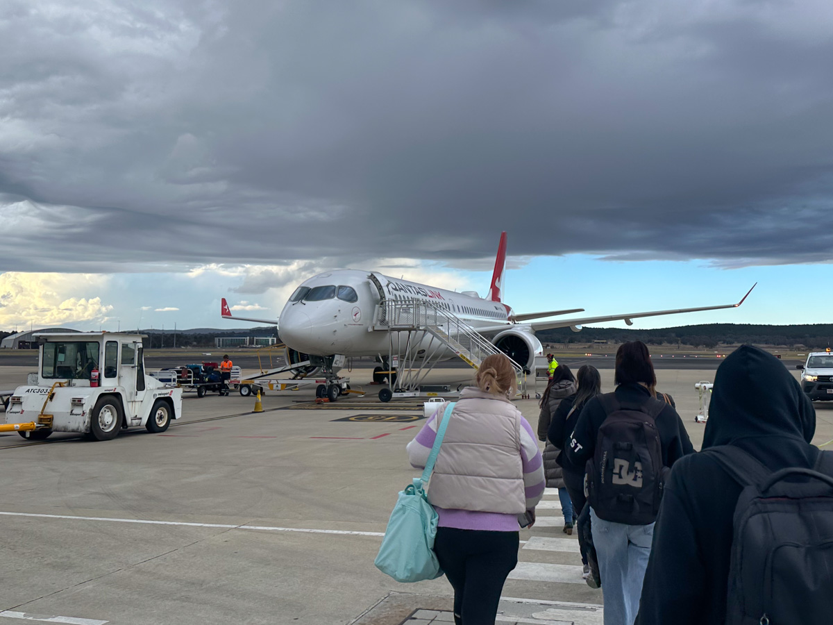 Boarding a QantasLink A220-300 at Canberra Airport, passengers walking to the plane