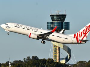 Virgin Australia Boeing 737-800 taking off at Sydney Airport with ATC air traffic control tower in background