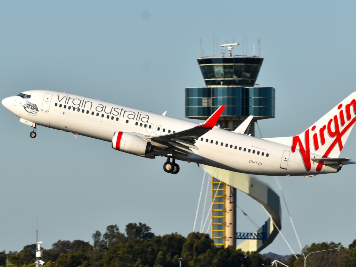 Virgin Australia Boeing 737-800 taking off at Sydney Airport with ATC air traffic control tower in background