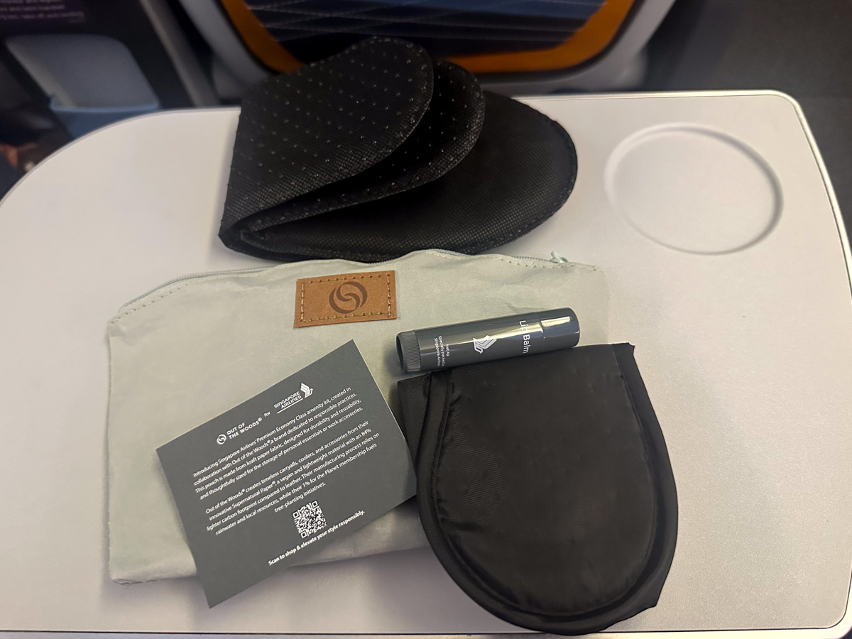 The contents of the Premium Economy amenity kit on Singapore Airlines with slippers, lip balm and an eye mask