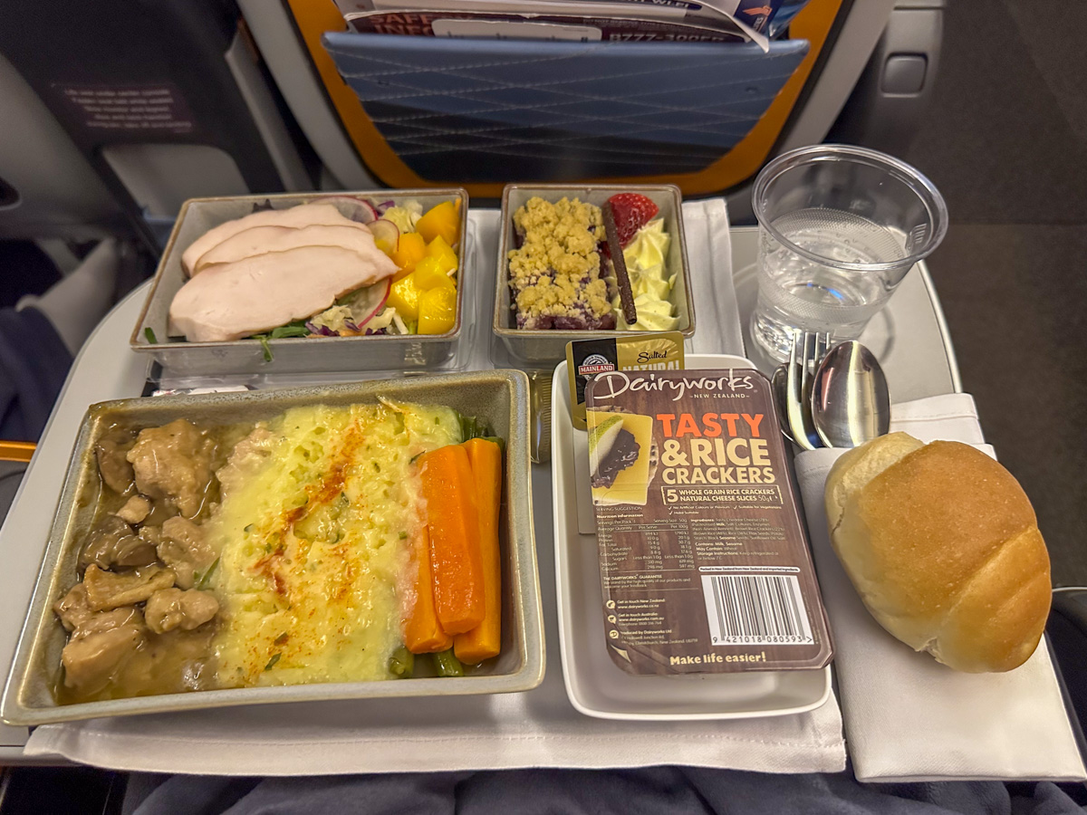 Singapore Airlines Premium Economy meal of Braised chicken in mushroom cream sauce with herby mango coleslaw and smoked chicken breast, alongside apple and berry crumble