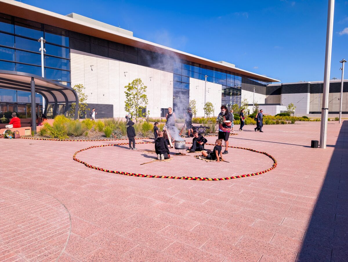 Aboriginal smoking ceremony inside a circle of red, yellow and black rope outside the WSI terminal