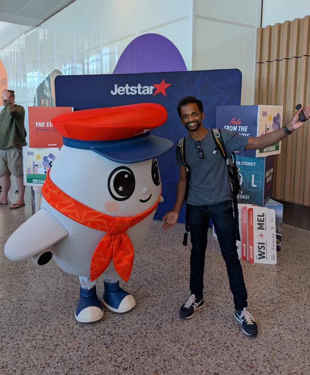 The author posing with the Jetstar mascot in front of a Jetstar backdrop at WSI